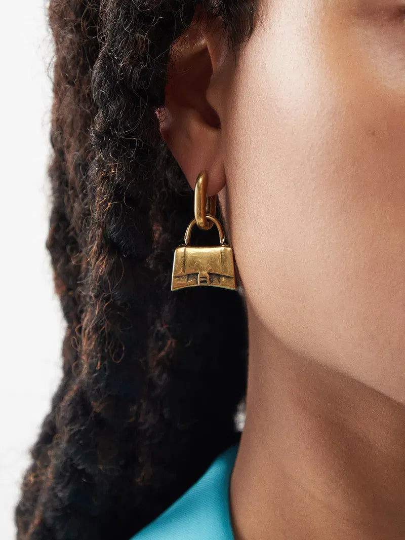 Balenciaga Hourglass Bag Stud Earrings in gold-tone, featuring a sleek, modern design with a distinctive hourglass shape.